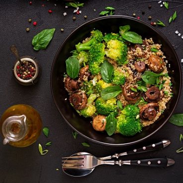 Dietary menu. Healthy vegan salad of vegetables - broccoli, mushrooms, spinach and quinoa in a bowl. Flat lay. Top view